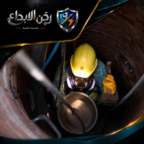 تسليك المجاري بالضغط في الفجيرة 0553689103 ركن الابداع فني يرتدي خوذة صفراء وكمامة واقية ويعمل بحذر داخل غرفة تفتيش عميقة لتنفيذ تسليك وصيانة الصرف