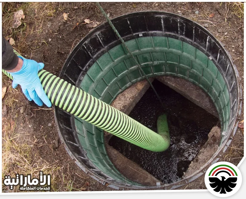 تسليك مجاري الحمام في دبي 0553689103 الإماراتية خرطوم شفط داخل غرفة صرف مفتوحة، ويظهر عامل يمسك الخرطوم لتنظيف أو سحب مياه المجاري والرواسب.
